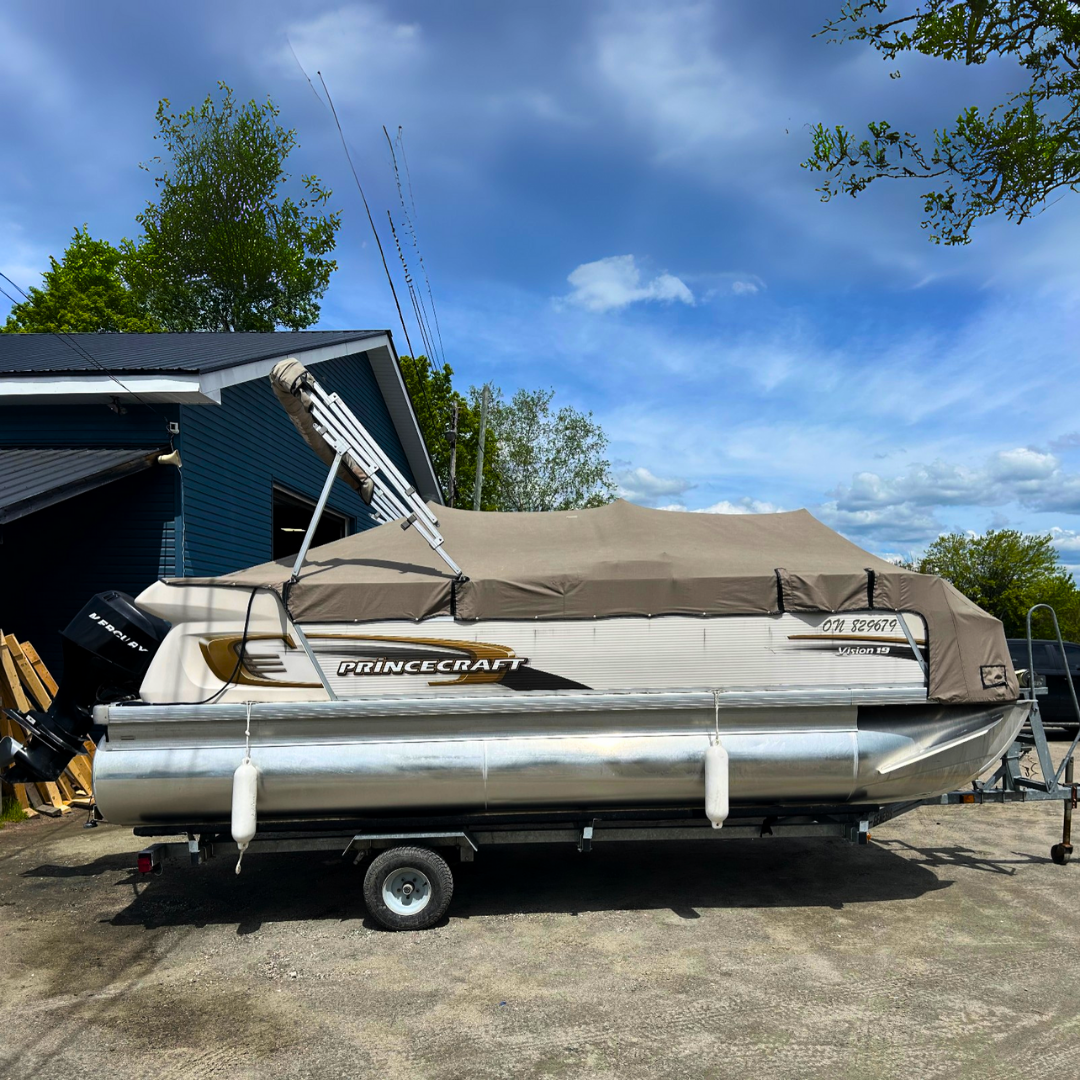 Pontoon boat on a trailer with a Princecraft logo, parked outdoors at marina