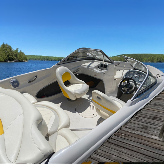 Yellow and white boat docked in a lake with treelined shore