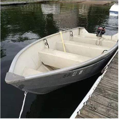 A small motorboat tied to a dock, primarily gray in color, with visible steering and motor.